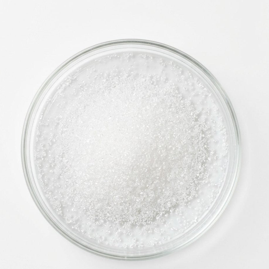 Clear glass plate with white granulated sugar on a white background